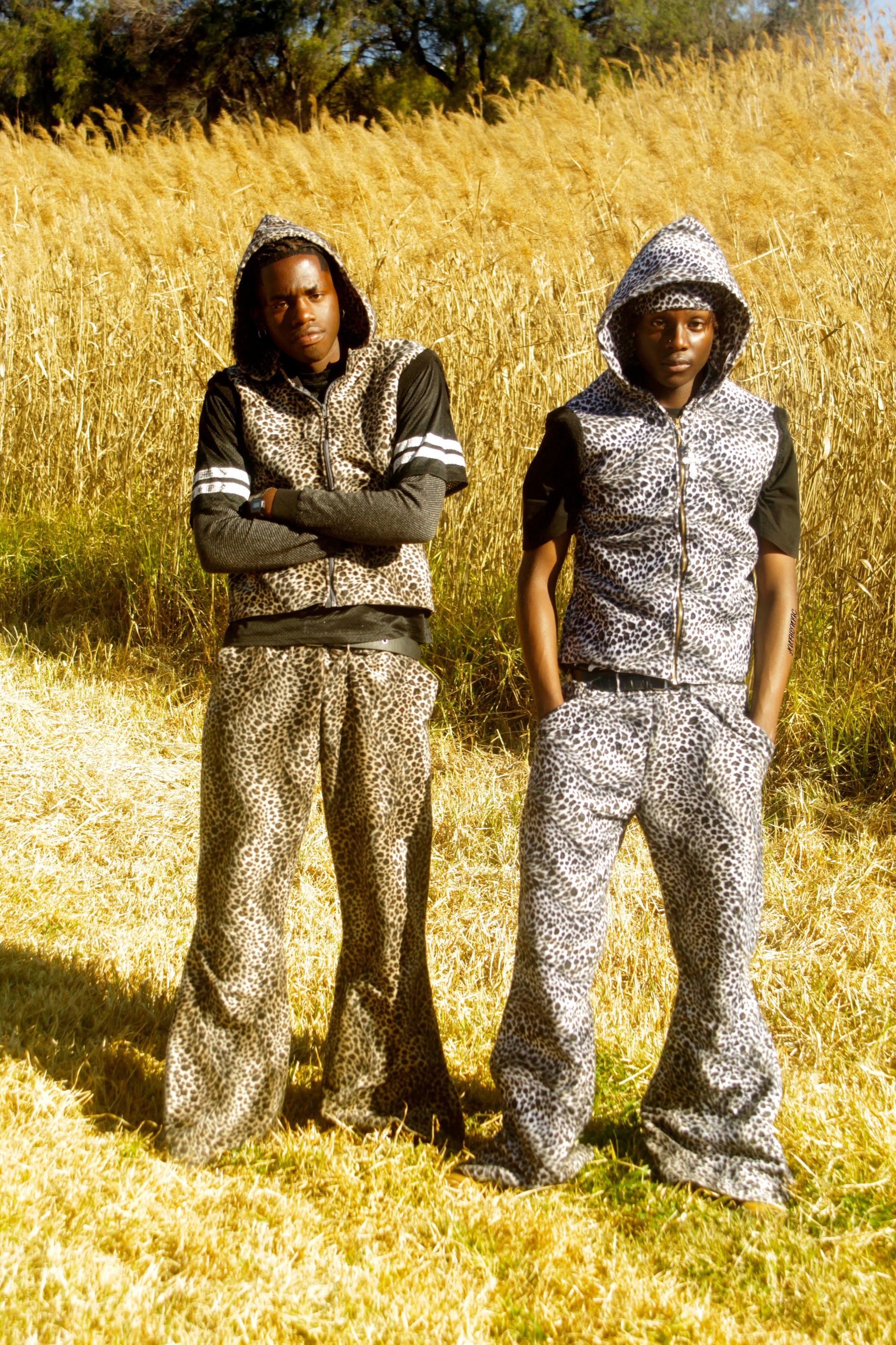 Two people wearing matching animal skin outfits standing in a field.